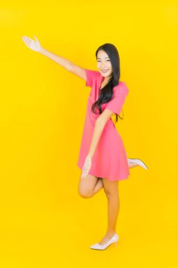 Asyalı güzel bir kadının portresi. Sarı arka planda hareketli gülümsüyor.