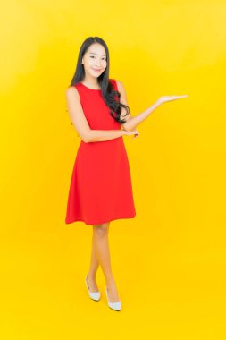 Güzel bir portre genç Asyalı kadın kırmızı elbiseler giyip sarı arka planda hareketli bir gülümseme takın.