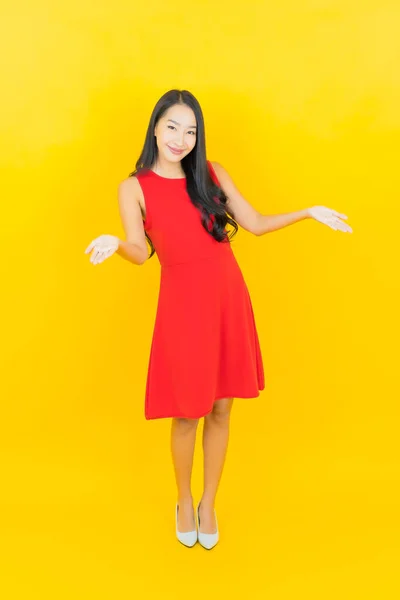 亚洲年轻貌美的女人穿着红色衣服 脸上挂着黄褐色背景的动作 — 图库照片