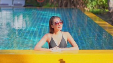 Güzel, genç Asyalı bir kadının dinlenme, dinlenme, deniz kenarında yüzme havuzu, tatil için deniz kenarında yüzme görüntüsü.