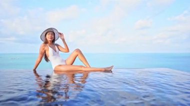 Güzel, genç Asyalı bir kadının dinlenme, dinlenme, deniz kenarında yüzme havuzu, tatil için deniz kenarında yüzme görüntüsü.