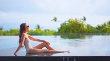 Güzel, genç Asyalı bir kadının dinlenme, dinlenme, deniz kenarında yüzme havuzu, tatil için deniz kenarında yüzme görüntüsü.