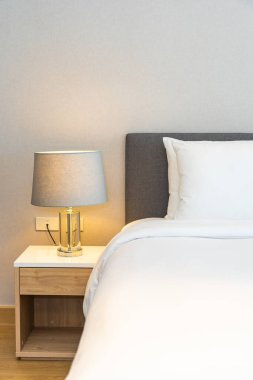 Yatak odasının iç dekorasyonuna beyaz yastık ve battaniye. İçinde lamba var.