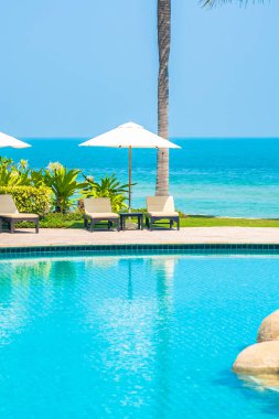 Açık yüzme havuzu, deniz kıyısı, şemsiye ve tatil için sandalye.