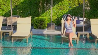 Güzel, genç Asyalı bir kadının dinlenme, dinlenme, deniz kenarında yüzme havuzu, tatil için deniz kenarında yüzme görüntüsü.