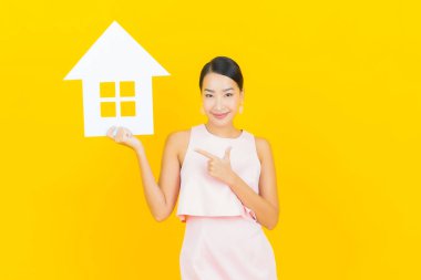 Sarı arka planda ev ya da kağıt tabelalı güzel Asyalı kadın portresi