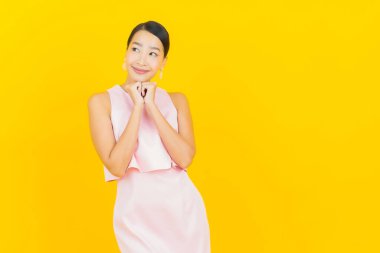 Asyalı güzel bir kadının portresi. Sarı arka planda hareketli gülümsüyor.