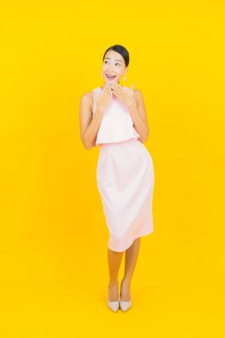 Asyalı güzel bir kadının portresi. Sarı arka planda hareketli gülümsüyor.