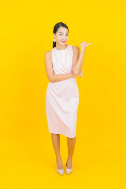 Asyalı güzel bir kadının portresi. Sarı arka planda hareketli gülümsüyor.