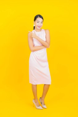 Asyalı güzel bir kadının portresi. Sarı arka planda hareketli gülümsüyor.