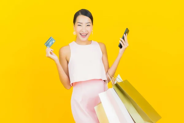 亚洲年轻貌美的女人带着黄色背景的购物袋微笑 — 图库照片