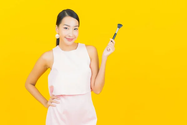 Sarı Arka Planda Makyaj Fırçası Kozmetik Olan Güzel Asyalı Kadın — Stok fotoğraf