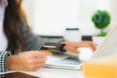 Güzel bir Asyalı kadının portresi online alışveriş malzemesi olarak dizüstü bilgisayarla kredi kartı kullanıyor.