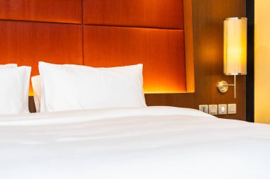 Beyaz yastık ve battaniye yatak odasının içinde lamba süslemesi olan yatakta.