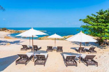 Güzel tropikal sahil denizi, şemsiyesi ve sandalyesi ile beyaz bulut ve mavi gökyüzü tatil seyahati için