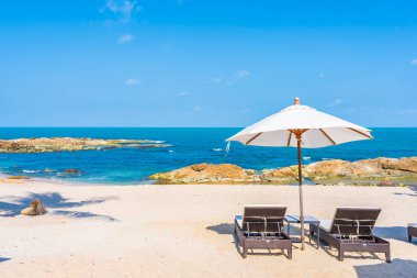 Güzel tropikal sahil denizi, şemsiyesi ve sandalyesi ile beyaz bulut ve mavi gökyüzü tatil seyahati için