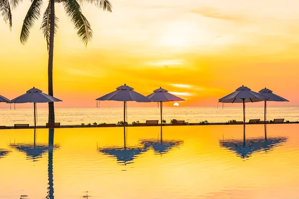 夕日や日の出の時間に海のビーチやヤシの木とホテルのリゾート地でプールの周りの傘デッキチェア — ストック写真