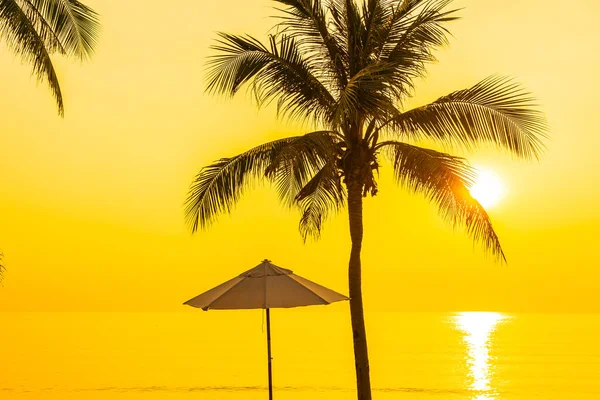 日落或日出时带着椰子树环抱着海滩海的伞状和甲板椅 供游玩 — 图库照片