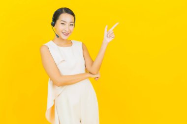 Sarı arka planda çağrı merkezi müşteri hizmetleri merkezi olan güzel Asyalı kadın portresi