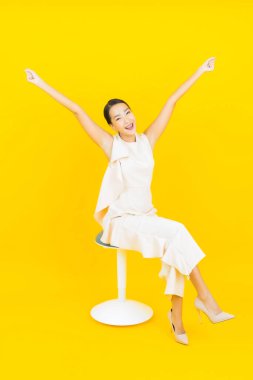 Asyalı güzel bir kadının portresi. Sarı arka planda hareketli gülümsüyor.