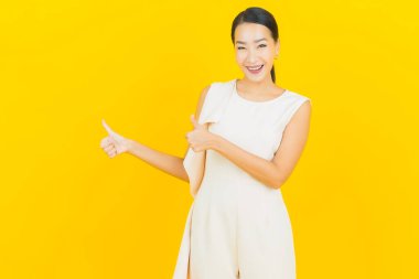 Asyalı güzel bir kadının portresi. Sarı arka planda hareketli gülümsüyor.