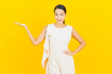 Asyalı güzel bir kadının portresi. Sarı arka planda hareketli gülümsüyor.