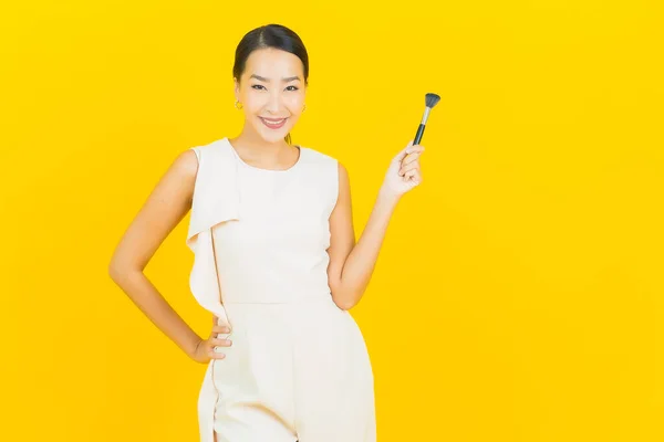노란색 배경에 화장품을 아름다운 아시아 여자의 — 스톡 사진