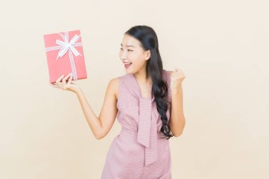 Güzel bir Asyalı kadının portresi. Arka planda kırmızı hediye kutusuyla gülümsüyor.