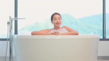 Güzel Asyalı kadının sabun köpüğüyle banyo yaptığı görüntüler.