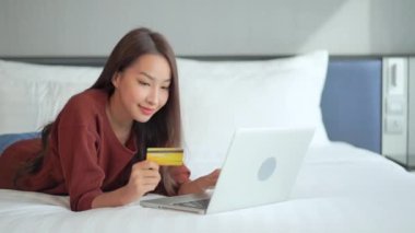 Güzel Asyalı kadının evde dizüstü bilgisayarla e-alışveriş yaptığı görüntüler. 