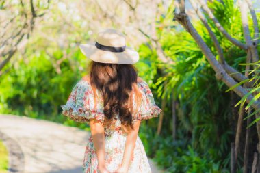 Güzel bir Asyalı kadın portresi. Mutlulukla yürüyor, bahçe manzarasının tadını çıkarıyor.