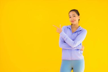 Sarı izole edilmiş arka planda spor giysili güzel Asyalı kadın portresi egzersize hazır.