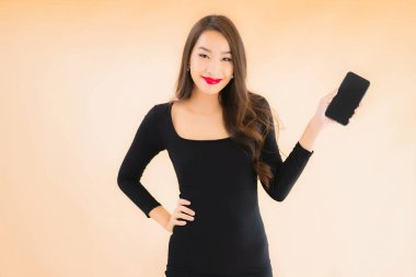 Güzel Asyalı genç bir kadının portresi mutlu bir şekilde gülümsüyor renkli arka planda akıllı cep telefonu kullan