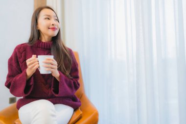 Portre güzel Asyalı kadın gülümsemesi. Oturma odasındaki kanepede rahatla.