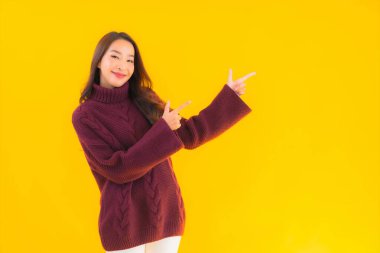 Güzel Asyalı kadın gülümsüyor. Sarı izole edilmiş arka planda başka bir eylemde mutlu.