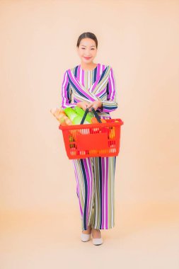 Marketten aldığı alışveriş sepetiyle güzel bir Asyalı kadının portresi. Renkli, izole arka plan.