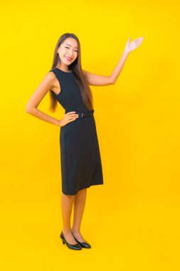 Güzel Asyalı iş kadını portresi. Sarı arka planda hareketli bir gülümseme.