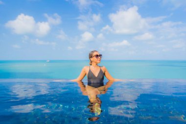 Güzel bir Asyalı kadın portresi. Rahatlayın. Okyanus manzaralı, tatil köyündeki yüzme havuzunda rahatlayın.