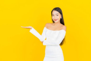 Portre güzel genç iş kadını gülümseyen ve eylem sarı arka planlı Asyalı kadın