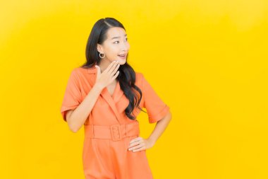 Asyalı güzel bir kadının portresi. Sarı arka planda hareketli gülümsüyor.