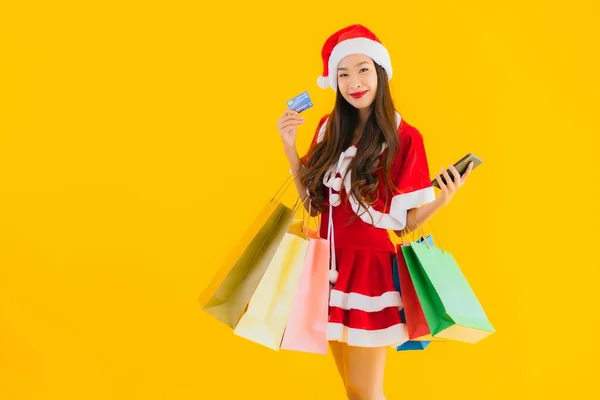 亚洲年轻貌美的女人 头戴圣诞礼帽 头戴黄色独立背景的购物袋 — 图库照片