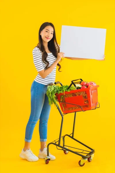 식품점 바구니를 가지고 노란색외진 배경에 판자가 아름다운 아시아 여인의 — 스톡 사진