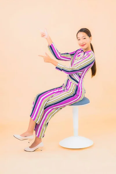 亚洲年轻貌美的女子坐在椅子上 微笑着 在与肤色隔离的背景上采取行动 — 图库照片