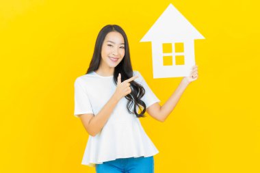 Sarı arka planda ev ya da kağıt tabelalı güzel Asyalı kadın portresi