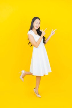 Asyalı güzel bir kadının portresi. Sarı arka planda hareketli gülümsüyor.