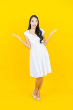 Asyalı güzel bir kadının portresi. Sarı arka planda hareketli gülümsüyor.