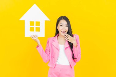 Sarı arka planda ev ya da kağıt tabelalı güzel Asyalı kadın portresi