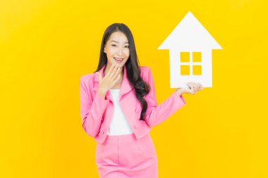 Sarı arka planda ev ya da kağıt tabelalı güzel Asyalı kadın portresi