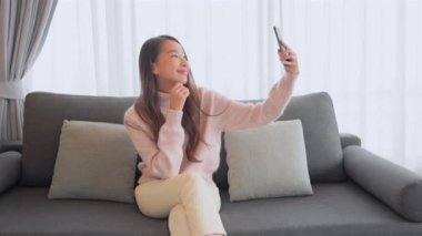 Güzel Asyalı kadının evde akıllı telefon kullandığının görüntüleri.