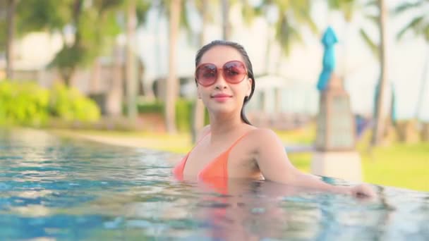美丽的年轻亚洲女人的镜头 在户外游泳池附近 在海滨度假时 放松地微笑 休闲一下 — 图库视频影像